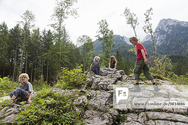 Brüder und Schwestern spielen auf Felsformationen im Wald  Zauberwald  Bayern  Deutschland