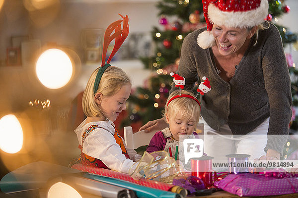 Mother and daughters wrapping Christmas presents