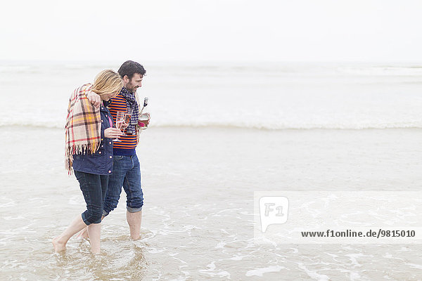 Couple walking in the sea  holding wine and wine glasses