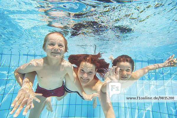 Unterwasseransicht von Mutter und zwei Söhnen beim Tauchen im Schwimmbad