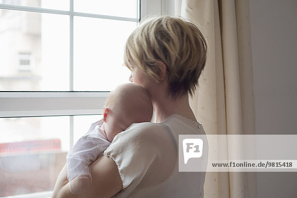 Mother carrying sleeping baby girl  looking out window