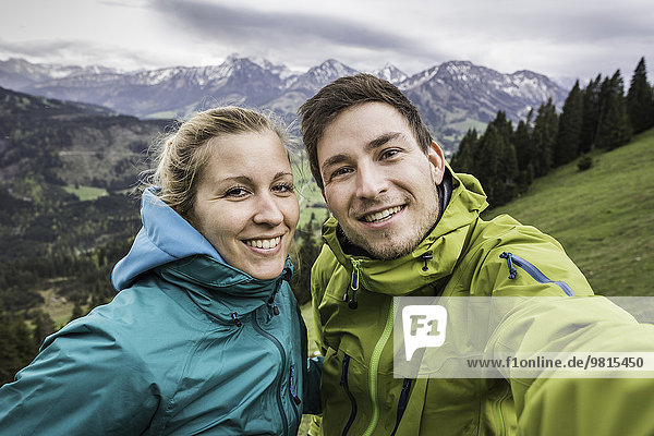 Young hiking couple taking self portrait  on the way down Zinken mountain  Oberjoch  Bavaria  Germany