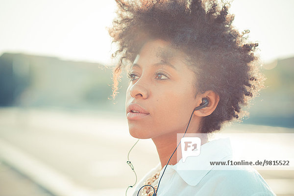 Porträt einer nachdenklichen jungen Frau beim Hören von Kopfhörern