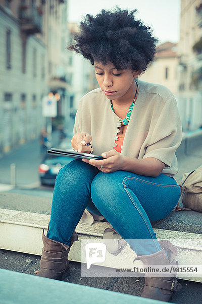 Junge Frau mit Touchscreen auf digitalem Tablett am Dachrand