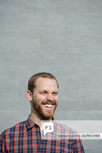 Porträt eines lachenden jungen Mannes in kariertem Hemd