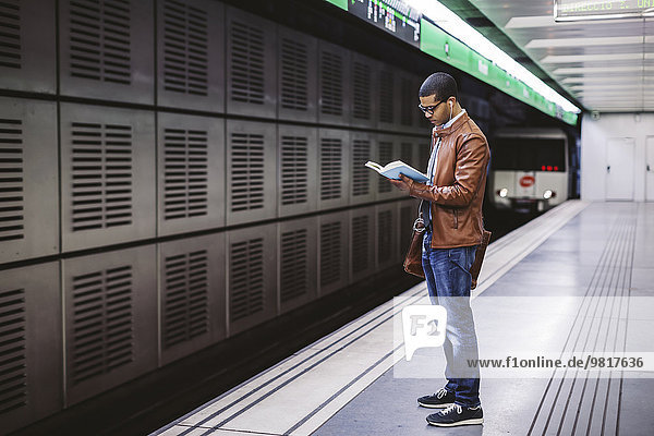 Spanien  Barcelona  Geschäftsmann steht am U-Bahnhof Bahnsteig und liest Buch