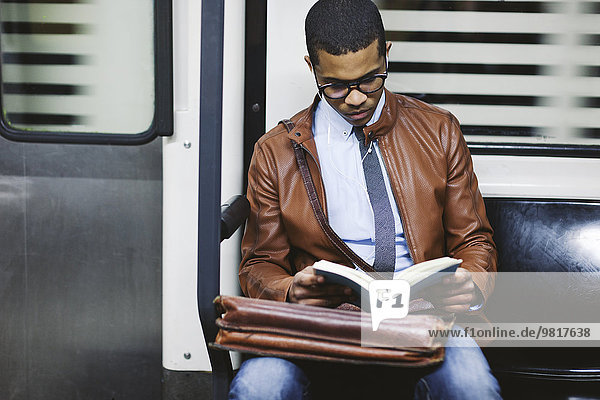 Businessman reading book on the subway train