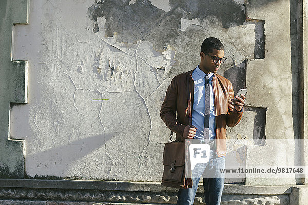 Geschäftsmann mit Smartphone in Lederjacke und Brille