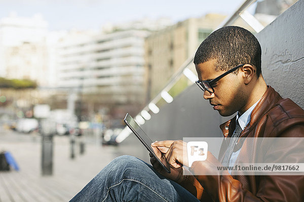 Geschäftsmann sitzt draußen mit Mini-Tablette