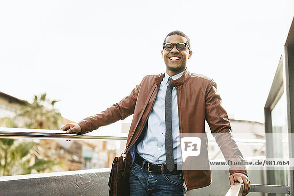 Portrait eines lachenden Geschäftsmannes mit Lederjacke und Brille