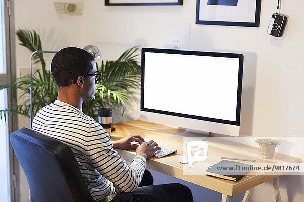 Junger kreativer Mann arbeitet am Computer in seinem Home-Office