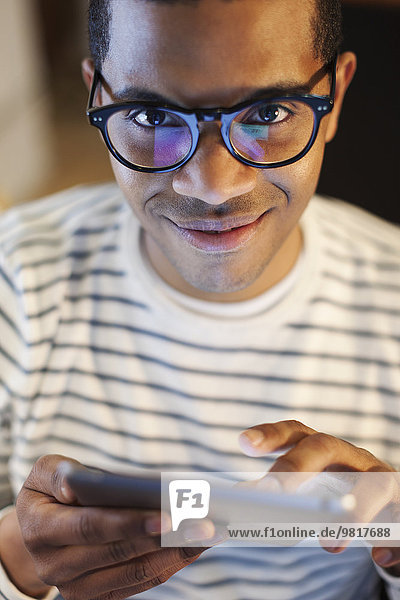 Portrait of smiling young man using mini tablet