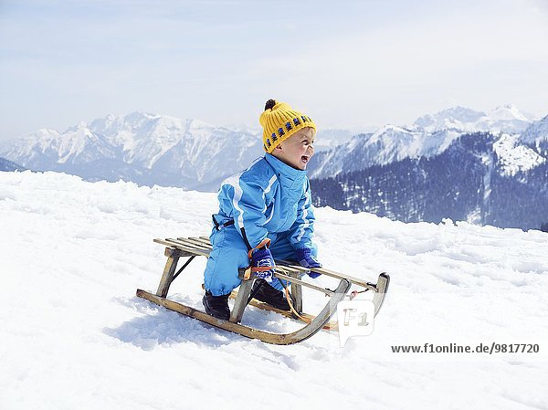 Germany  Tegernsee  Wallberg  smiling little boy sitting on sledge