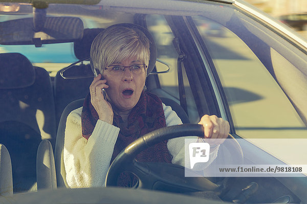 Frightened senior woman in car on cell phone