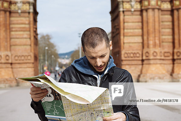 Spanien  Barcelona  Mann schaut auf Stadtplan vor dem Trymphalbogen