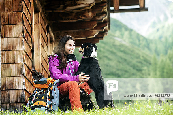 Österreich  Altenmarkt-Zauchensee  junge Frau und Hund vor einer Alpinhütte