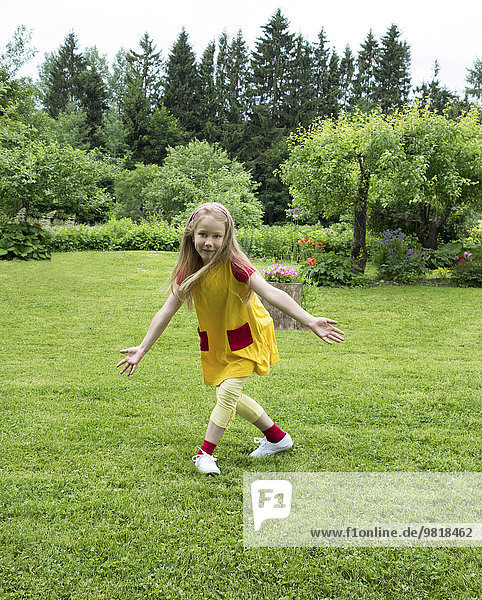 Estland  lächelndes Mädchen tanzt auf dem Rasen