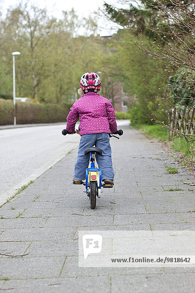 Germany  Kiel  Little girl riding bicycle  rear view