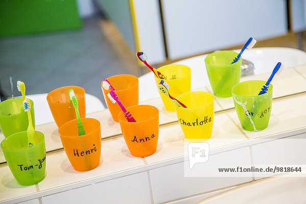 Kunststoffbecher mit Zahnbürsten mit Mähnen von Kindern im Kinderzimmer Kunststoffbecher mit Zahnbürsten mit Mähnen von Kindern im Kinderzimmer