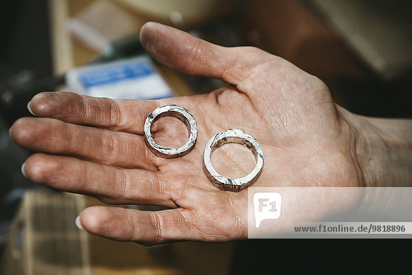 Goldsmith working on wedding rings in Mokume Gane style  hand holding unfinished ring