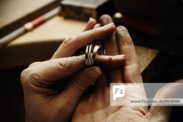Goldschmiedin arbeitet an Eheringen  Hand hält unfertigen Ring