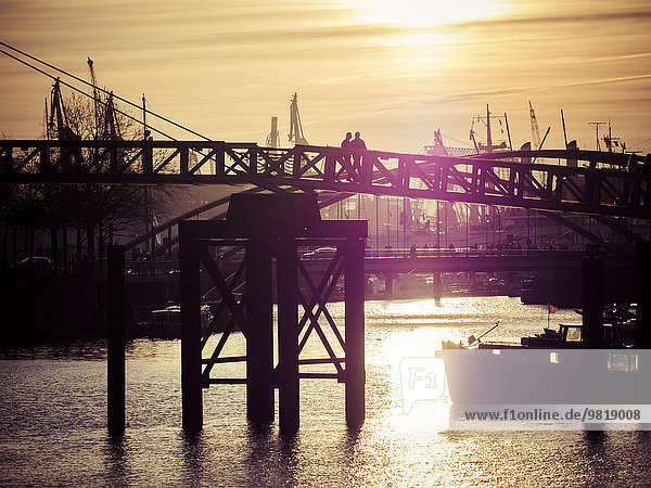 Deutschland  Hamburg  Hamburger Hafen  Elbe  Silhouetten von Personen auf der Brücke bei Sonnenuntergang