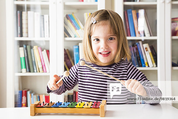 Portrait of happy little girl playing xylophones