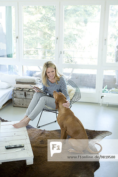 Frau mit Hund und digitalem Tablett zu Hause
