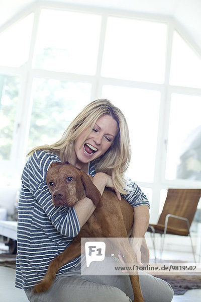 Woman playing with her dog at home