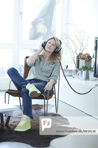Frau hört Musik mit Kopfhörern zu Hause