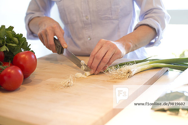 Nahaufnahme einer Frau beim Schneiden von Gemüse in der Küche