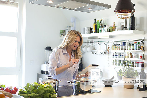 Frau mit digitalem Tablettenkochen in der Küche