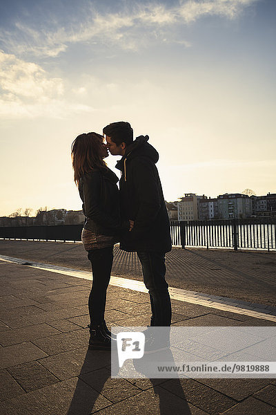 Deutschland  Berlin  Teenagerpaar beim Küssen auf einer Promenade am See