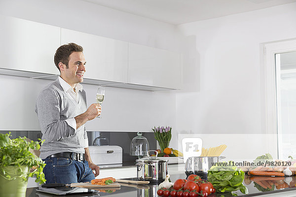 Man relaxing with glass of sparkling wine in kitchen