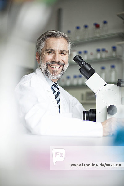 Porträt eines lächelnden Wissenschaftlers im Labor mit Mikroskop