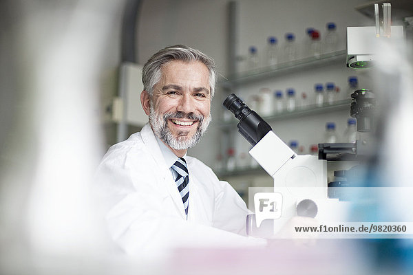 Porträt eines lächelnden Wissenschaftlers im Labor mit Mikroskop