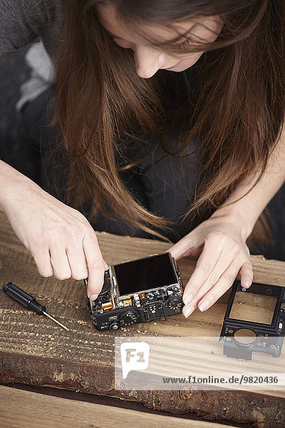 Young woman repairing camera