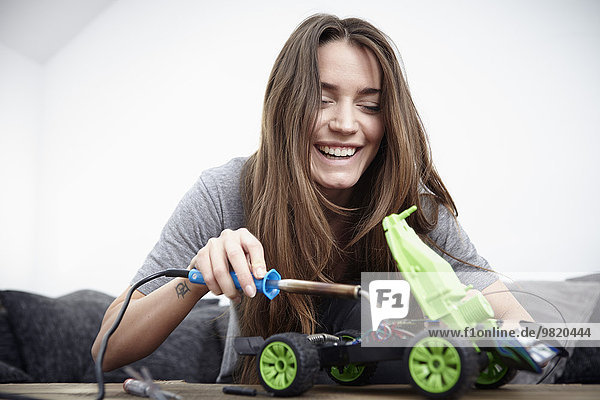 Junge Frau repariert Spielzeugauto