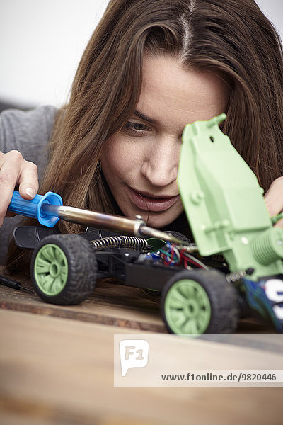 Junge Frau repariert Spielzeugauto