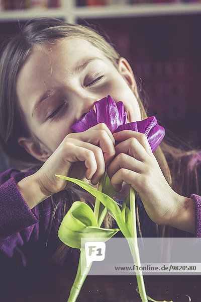 Kleines Mädchen mit geschlossenen Augen duftende Tulpen