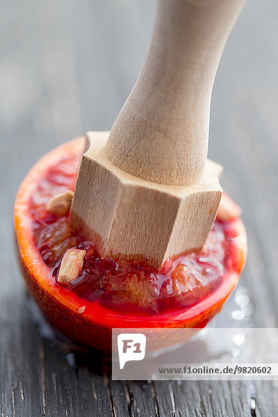 Wooden juice squeezer squeezing half of blood orange
