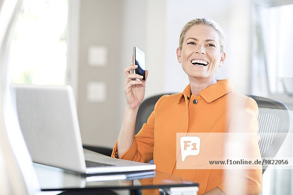 Portrait of businesswoman with smartphone at desk in an office