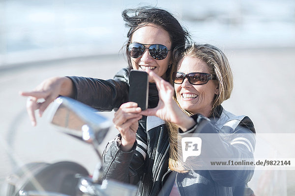 Zwei Frauen auf dem Motorrad  die Selfie nehmen.