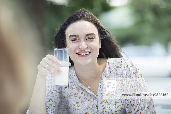 Happy young woman with milk mustache outdoors