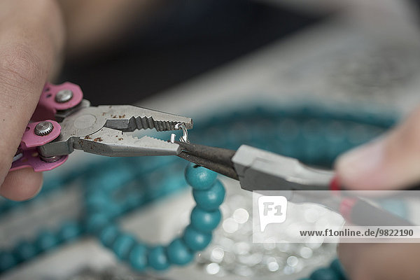 Close-up of woman working with pliers to create a bead necklace