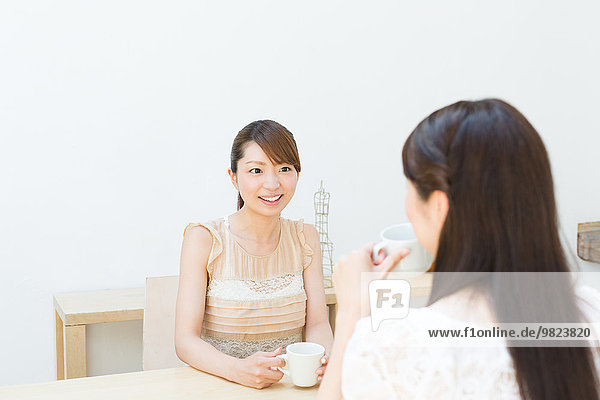 Attractive young girls chatting over a cup of coffee