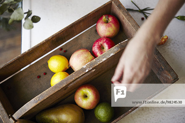 Fruits in wooden box  hand on foreground