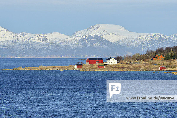 Landzunge mit Häusern im blauen Wasser von Hadselfjord und Raftsund  Vesterålen  Nordland  Norwegen  Europa