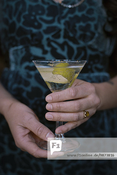 Frau Glas halten Cocktail verdreht Schale Zitrusfrucht Zitrone Martini