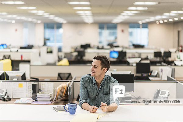 Ein junger Mann  der an einem Schreibtisch in einem Büro sitzt.